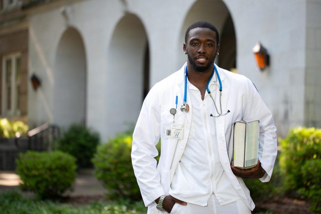 Male student nurse holding text books outdoors