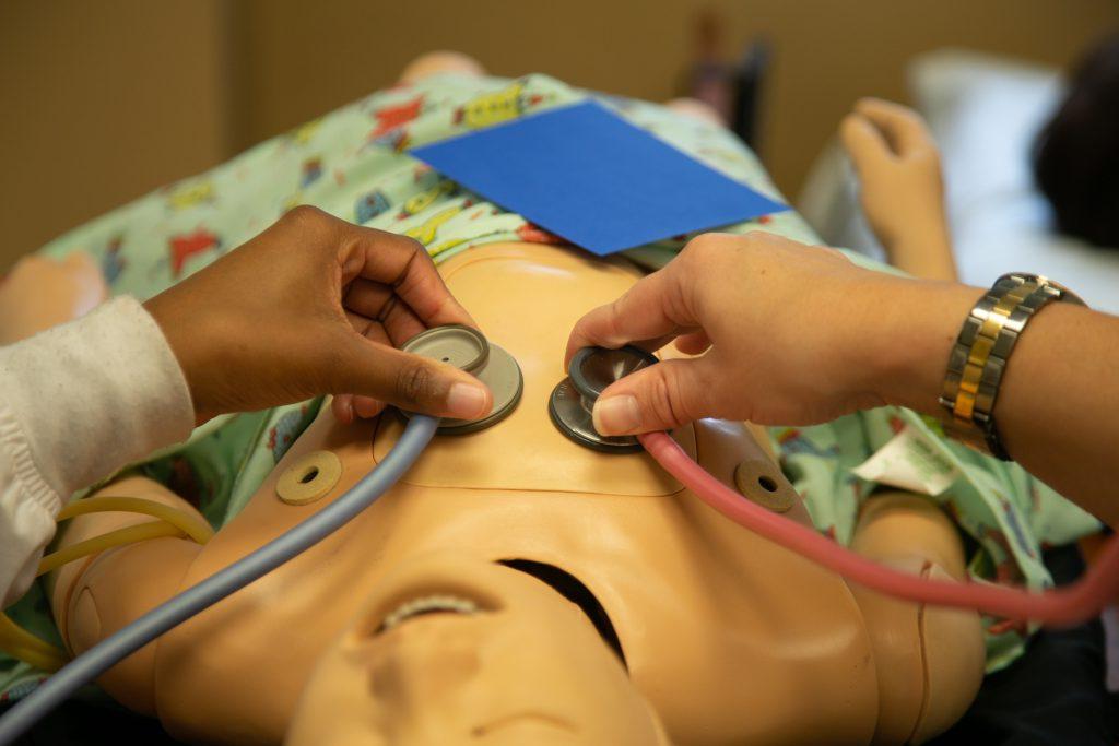 Two nursing students work on a simulated patient