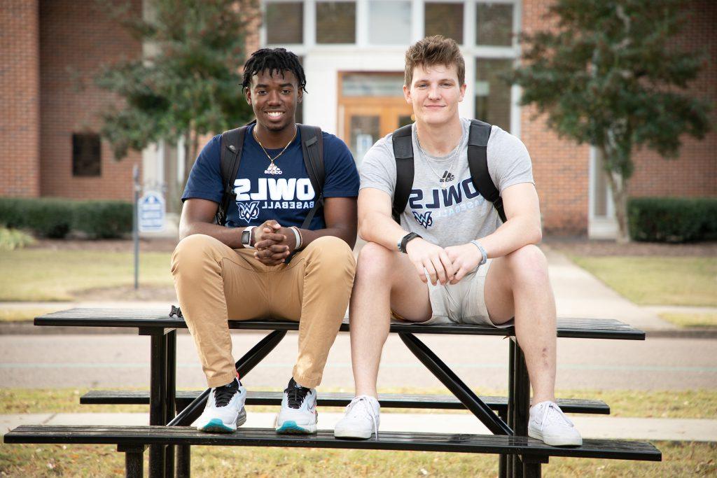 Two male students sit on a bench outdoors